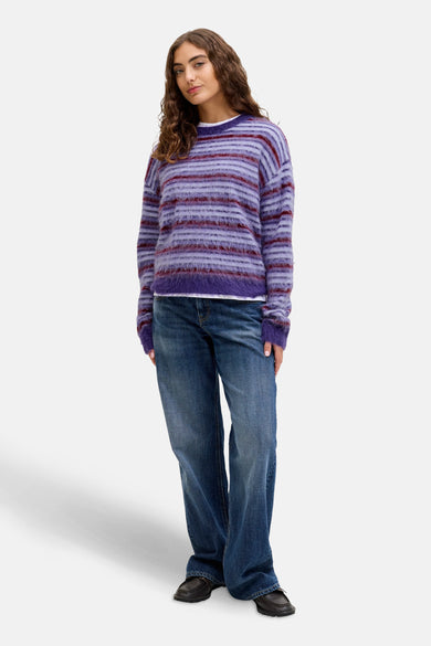 Paarse ronde hals trui van JJXX, met horizontale strepen en gedragen met wijde jeans en bruine schoenen.
