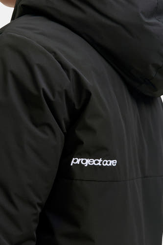 Zwarte korte jas van CORE BY JACK & JONES met subtiele ripstop textuur, capuchon en wit "project core" borduursel.
