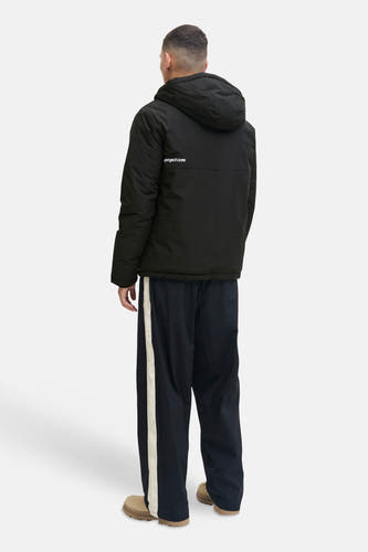 Zwarte korte jas van CORE BY JACK & JONES met capuchon en 'project core' op de rug, gedragen door een man, achteraanzicht.