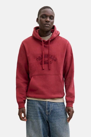 Pull-over rouge avec capuche d'ORIGINALS BY JACK & JONES, porté sous une veste beige et des jeans larges.