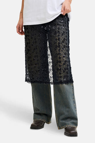 Lange zwarte rok van JJXX, met bloempatroon en pailletten, gecombineerd met een witte top, jeans en bruine schoenen.
