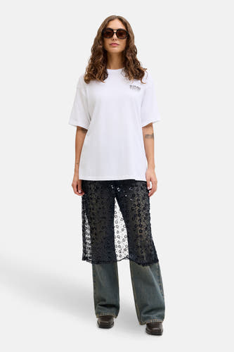 Lange zwarte rok van JJXX, met een bloemenpatroon en pailletten, gedragen over een blauwe jeans.
