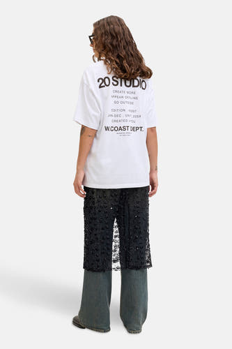 Lange zwarte rok van JJXX, met bloemmotief, gecombineerd met een wit T-shirt en wijde jeans.
