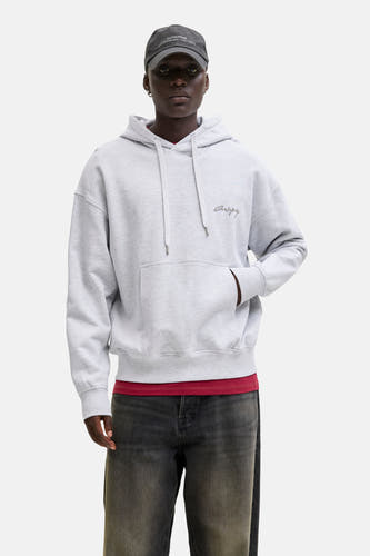 Grijze sweater met kap van ORIGINALS BY JACK & JONES, met een buidelzak en gecombineerd met een pet en spijkerbroek.
