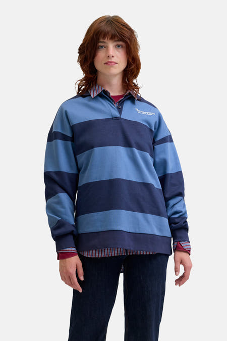 Pull-over bleu de JJXX, avec des rayures horizontales, associé à un chemisier à carreaux et à des jeans foncés.