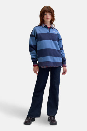 Blauwe sweater van JJXX, met horizontale strepen, gecombineerd met een geruit overhemd en donkere jeans.