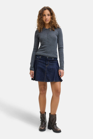 Short skirt of dark blue denim from JJXX, combined with a gray top with long sleeves and brown boots.