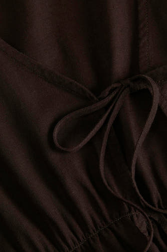 Bruine blouse van JJXX met V-hals, strikdetail en fijne textuur, close-up.