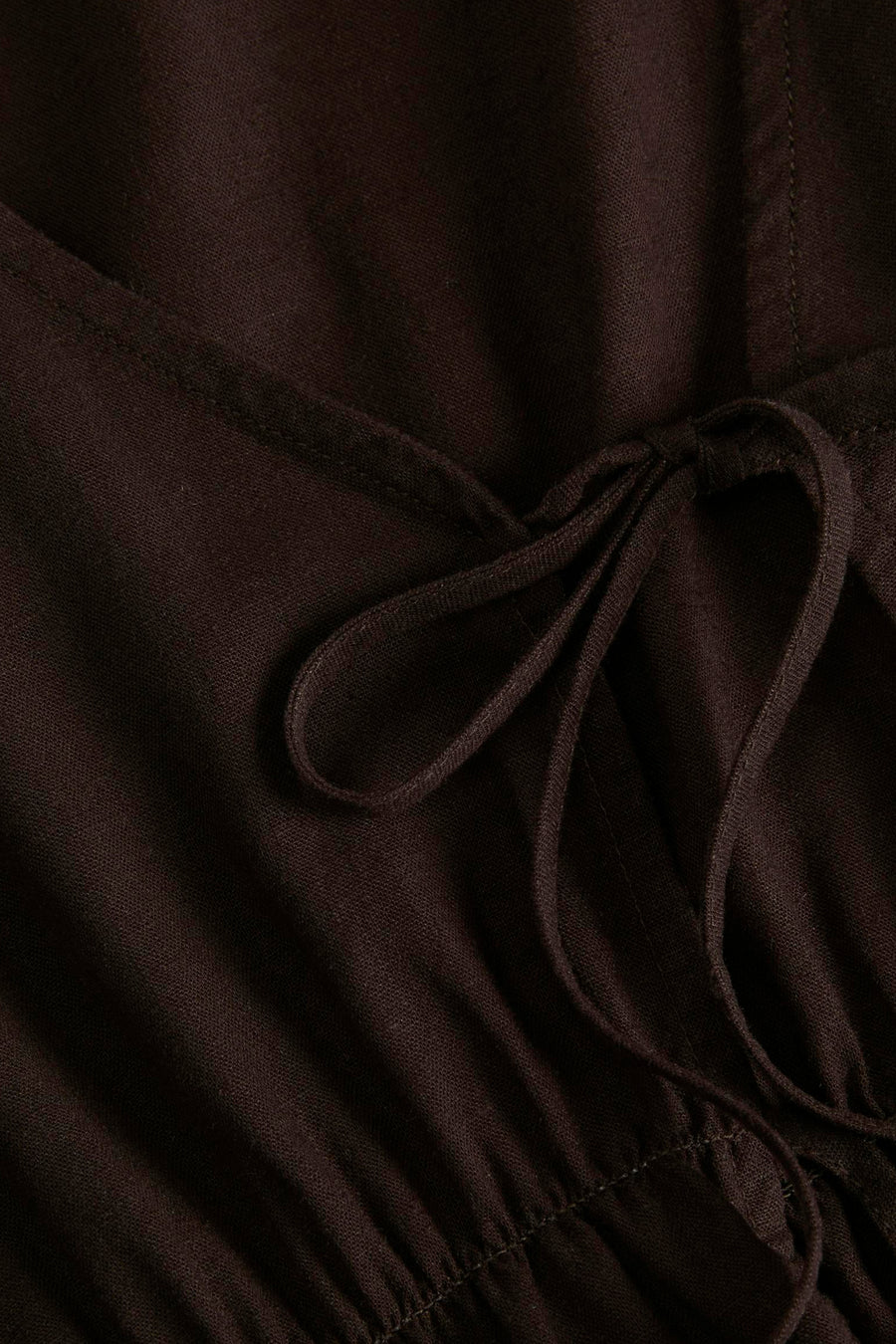 Bruine blouse van JJXX met V-hals, strikdetail en fijne textuur, close-up.