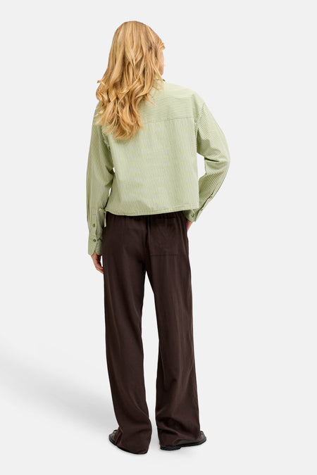 Bruine broek van JJXX, met wijde pijpen, en een elastische tailleband, gezien van achteren.
