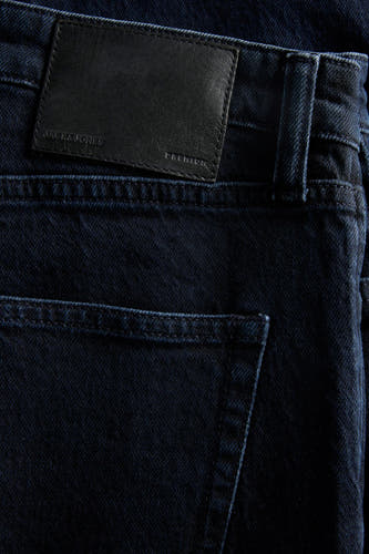 Jean tapered bleu marine de JACK & JONES JEANS INTELLIGENCE, avec une patch en cuir noir et un détail de poche arrière.