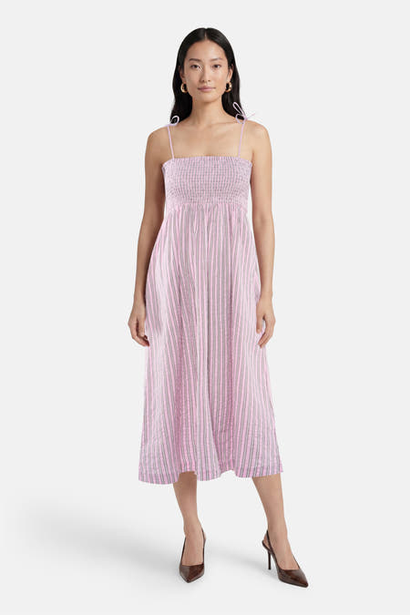 Roze mouwloze jurk van JJXX met smockdetail, verticale strepen en spaghettibandjes, gedragen door een model.