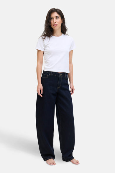 Donkerblauwe denim jeans special fit van JJXX, gedragen met een wit T-shirt en blote voeten.
