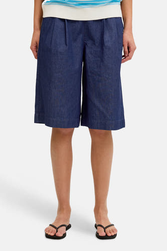Donkerblauwe denim shorts van JJXX, met plooien aan de taille, gedragen met een gestreept shirt en slippers.