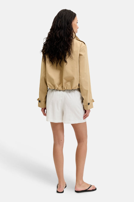 Witte Short van JJXX met textuur, gedragen met een beige jasje en zwarte slippers, vanuit de rug gezien.