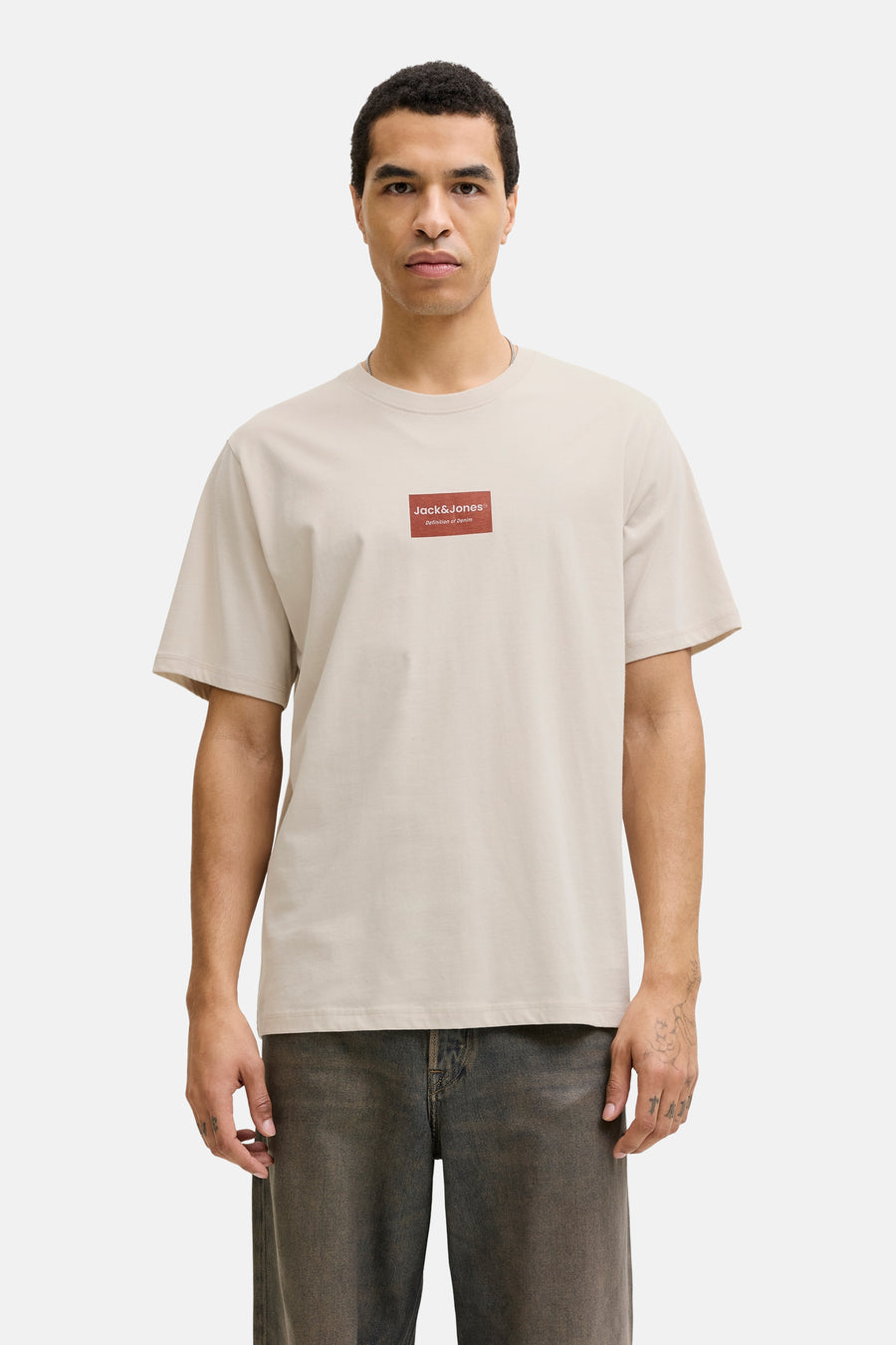 Beige T-shirt met korte mouwen van CORE BY JACK & JONES, met een rood logo-embleem op de borst.