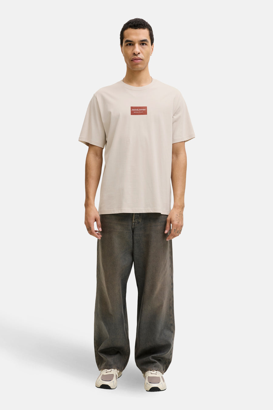 Beige T-shirt met korte mouwen van CORE BY JACK & JONES, gedragen met wijde jeans en sneakers.
