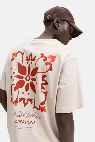 Beige T-shirt van ORIGINALS BY JACK & JONES, gezien van achteren, met een grote rode bloemenprint en tekst op de rug.