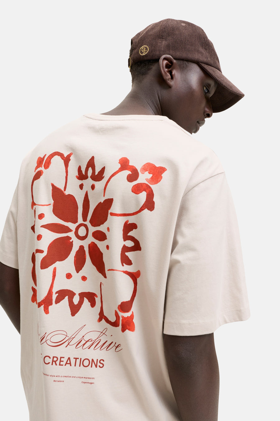 Beige T-shirt van ORIGINALS BY JACK & JONES, gezien van achteren, met een grote rode bloemenprint en tekst op de rug.
