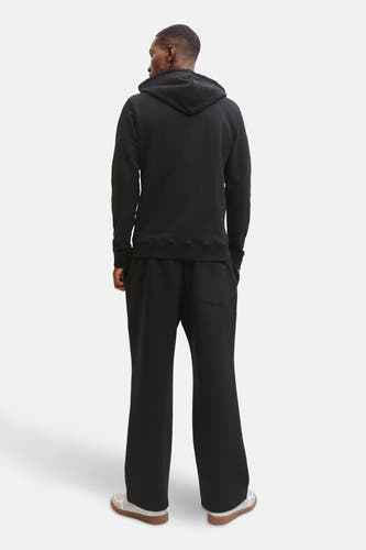 Zwarte sweater met kap van CORE BY JACK & JONES, gezien van achteren, met bijpassende zwarte broek en witte schoenen met bruine zolen.