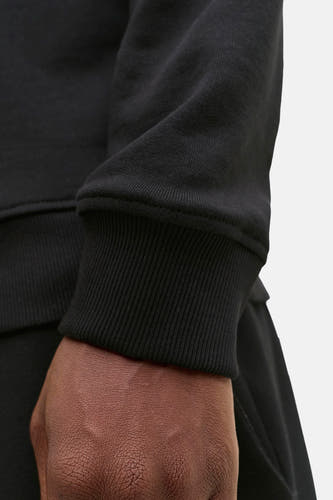 Zwarte sweater van CORE BY JACK & JONES, close-up detail van de geribbelde manchetten en de textuur van de stof.