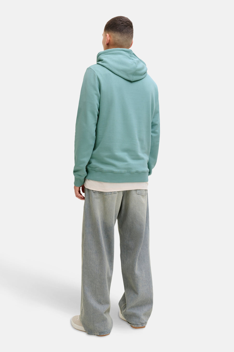 Pull vert avec capuche de CORE BY JACK & JONES, associé à des jeans décontractés et des chaussures crème.