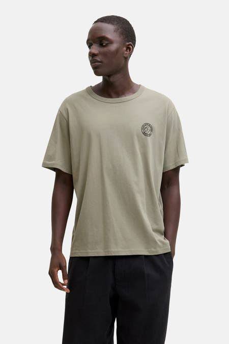Groen T-shirt met korte mouwen van ORIGINALS BY JACK & JONES, met klein logo op de borst en gedragen met zwarte broek.