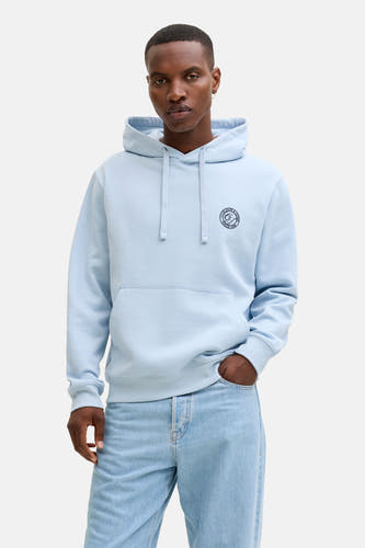 Pull-over bleu avec capuche d'ORIGINALS BY JACK & JONES, doté d'une impression ronde sur la poitrine, associé à des jeans bleus clairs et des chaussures noires.