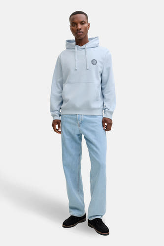 Blauwe sweater met kap van ORIGINALS BY JACK & JONES, met een ronde print op de borst, gecombineerd met lichtblauwe jeans en zwarte schoenen.