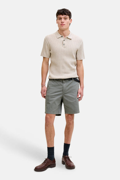 Beige polo trui van PREMIUM by JACK & JONES, met een kabelpatroon en gedragen met grijze shorts, sokken en schoenen.