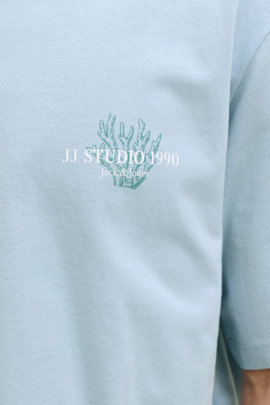 T-shirt en maille bleu de Jack & Jones avec un motif de corail vert et le texte 'JJ Studio 1990'.