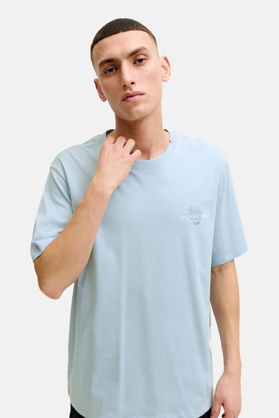 T-shirt bleu de ORIGINALS BY JACK & JONES avec imprimé corail subtil et le texte 'JJ STUDIO 1990 Jack & Jones' sur la poitrine, porté par un homme.