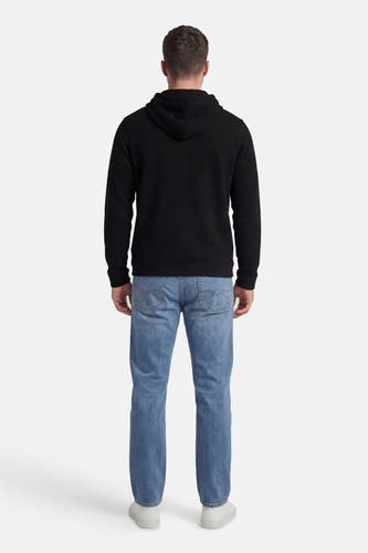 Zwarte sweater met kap van CORE BY JACK & JONES, achterkant, gecombineerd met blauwe jeans en witte sneakers.