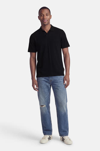 Zwarte polo met ribstructuur van CORE BY JACK & JONES, gedragen met gescheurde jeans en witte sneakers, front view.