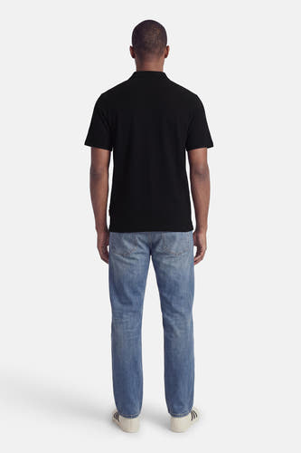 Zwarte polo van CORE BY JACK & JONES, achterkant, met ribstructuur, gedragen met blauwe jeans en witte sneakers