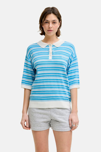 Blauwe trui van JJXX, met wit gestreepte details, een polokraag en gedragen met grijze shorts.
