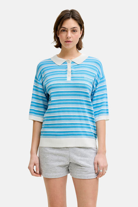 Blauwe trui van JJXX, met wit gestreepte details, een polokraag en gedragen met grijze shorts.
