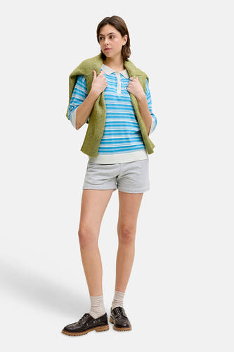 Blauwe gestreepte trui van JJXX, met een groene trui over de schouders, grijze shorts en bruine schoenen.