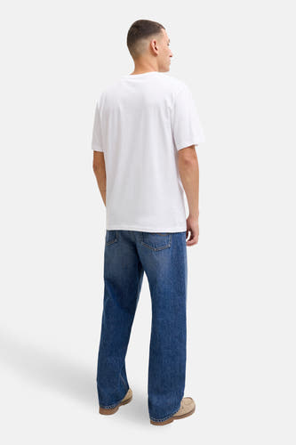 T-shirt blanc à manches courtes de CORE BY JACK & JONES, dos, associé à des jeans bleus et des chaussures en cuir suédé.