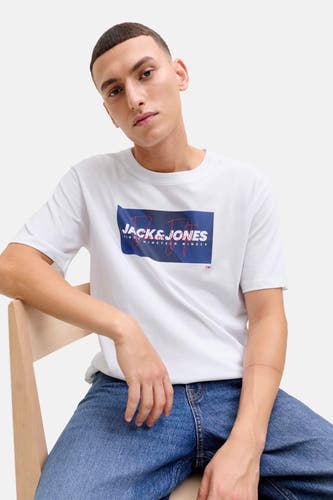 T-shirt blanc à manches courtes de CORE par JACK & JONES, avec un logo bleu-rouge sur la poitrine, porté avec un jean.