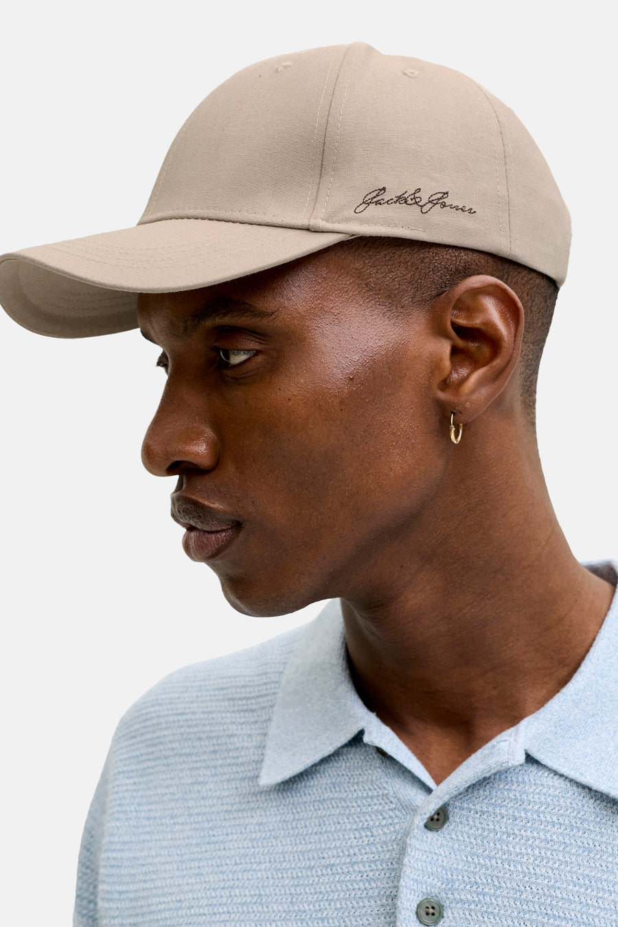 Beige pet van ACCESSORIES BY JACK & JONES met geborduurd logo, zijprofiel van model in lichtblauw poloshirt