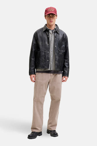 Pantalon beige de JACK & JONES JEANS INTELLIGENCE, associé à une veste en cuir noire, un chemisier rayé et une casquette bordeaux.
