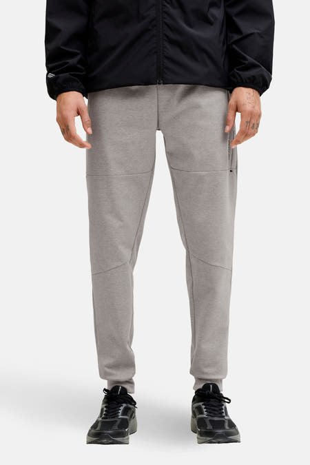 Grijze joggingbroek van JACK & JONES JEANS INTELLIGENCE, met zwarte sneakers en een zwart jack.
