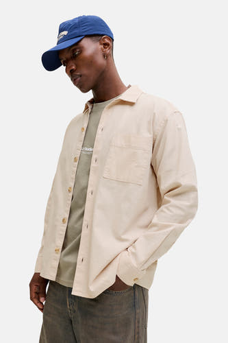 Chemise beige à manches longues de ORIGINALS BY JACK & JONES, portée sur un t-shirt vert et une casquette bleue.