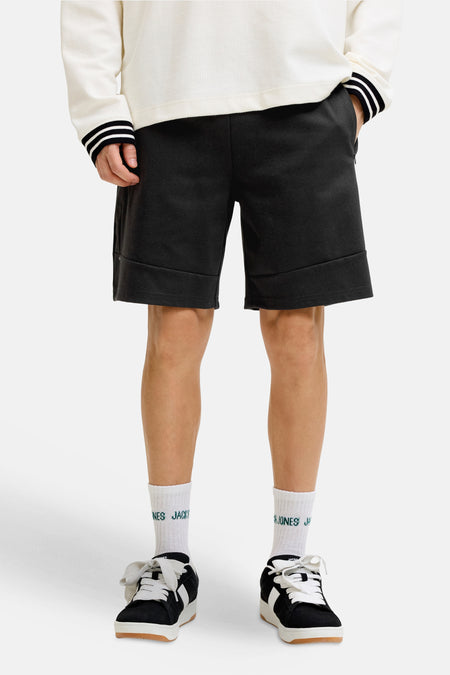 Short noir de JACK & JONES JEANS INTELLIGENCE, avec revers et associé à des chaussettes blanches et des baskets noires.