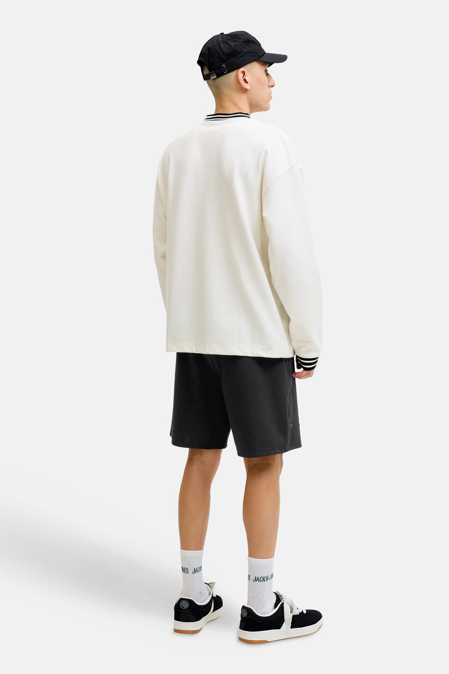 Short noir de JACK & JONES JEANS INTELLIGENCE, vu de dos, combiné avec un t-shirt ample, des chaussettes blanches et des chaussures noires.
