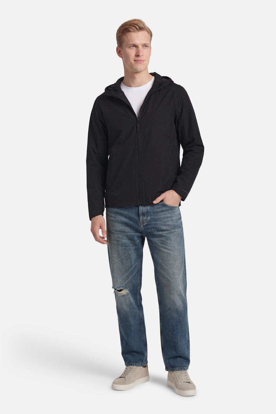 Veste courte noire de CORE by JACK & JONES, avec capuche, portée avec un t-shirt blanc et un jean bleu.