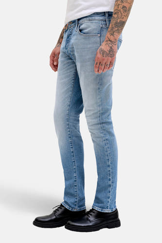Slim jeans van lichtblauw denim van JACK & JONES JEANS INTELLIGENCE, met tattoos op de hand en zwarte schoenen.
