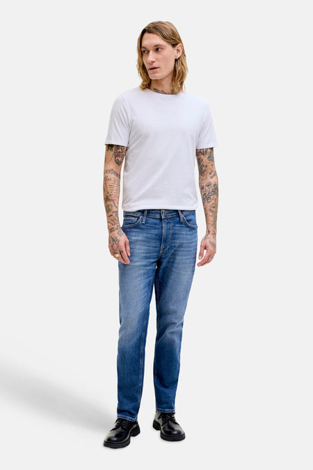 Rechte jeans van middenblauw denim van JACK & JONES JEANS INTELLIGENCE, gedragen door een man met een wit T-shirt en zwarte schoenen.