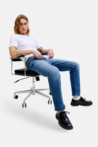 Mid blauwe denim rechte jeans van JACK & JONES JEANS INTELLIGENCE, gedragen door een zittende man met wit T-shirt en zwarte schoenen.